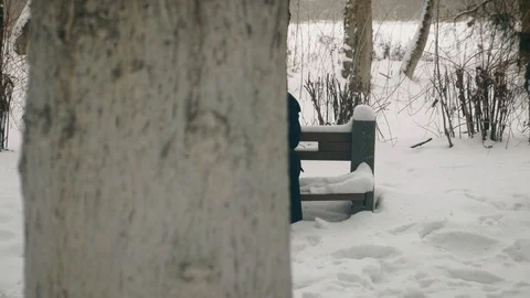 Point of interest shot: A man in a black coat sits thoughtfully on a bench in Stock Footage 102170137