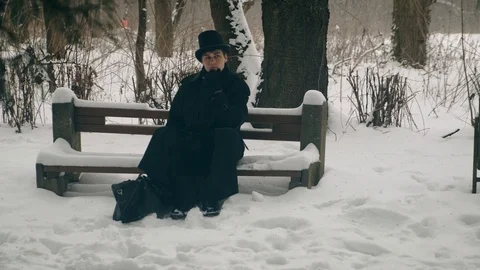 Point of interest shot: A man in a black coat sits thoughtfully on a bench in Stock Footage 102170602
