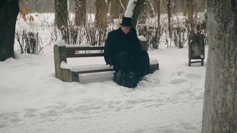 Point of interest shot: A man in a black coat sits thoughtfully on a bench in 動画素材 102170941