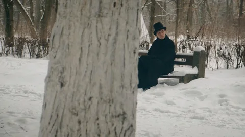 Point of interest shot: A man in a black coat sits thoughtfully on a bench in 動画素材 102171863