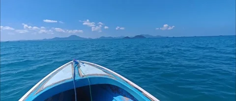Point of view from the bow of a small wooden boat sailing across a bright bl Video stock 335800449