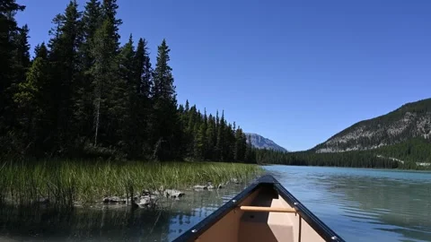 Point of view from a canoe paddling across a blue mountain lake with evergreen Stock Footage 333074919