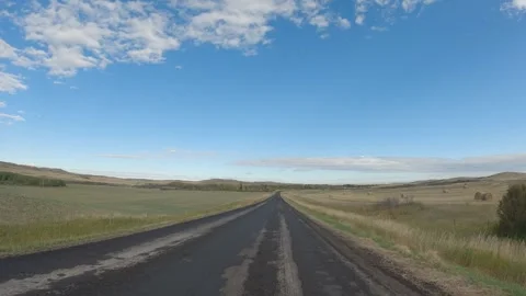 Point of view from car driving along a rough paved road through ranch land under Stock Footage 308587780