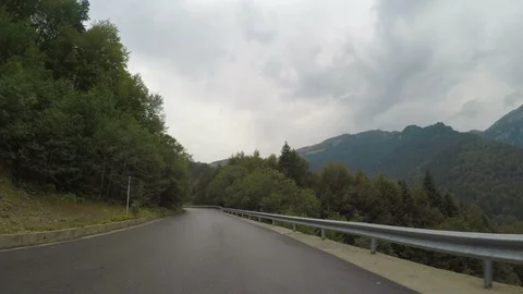 Point of view of car driving through alpine forest on winding road cloudy sky Stock Footage 86217003