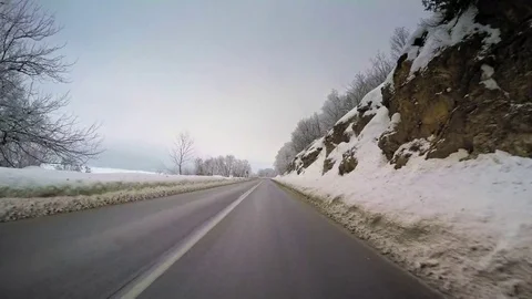 Point of view car travel winter mountain snow vehicle drive wet curvy road trees Stock Footage