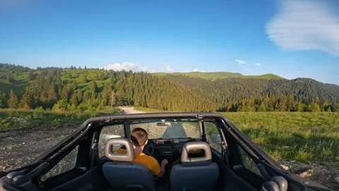 Point of view couple driving convertible off road car on wild mountain road Stock Footage 260827476