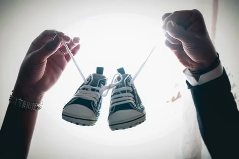 Point of view on couple holding each other's hand with baby shoes.parenthoo.. Stock Photos