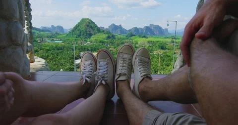Point Of View: Couple's feet overlooking the mountain coastline of Thailand Asia Stock Footage 201096005