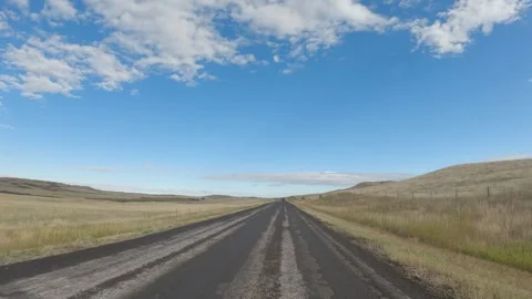 Point of view driving along a rough paved road through rolling ranch land under Stock Footage 306093564