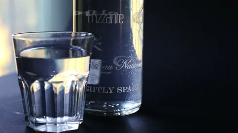 A point of view of a glass and bottle of sparkling water in a blue background Stock-Footage 56376322