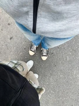 Point of view looking down at legs wearing jeans and shoes standing on asph.. Stock Photos