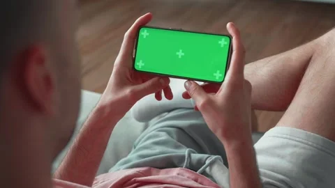 Point of View of man at Modern Room Sitting on a Chair Using Phone With Green Stock Footage 241746357