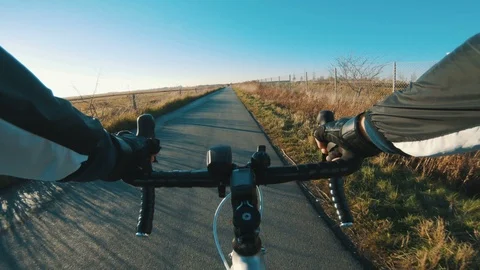 Point of view of man riding fast bicycle while sun sets in the horizon Stock Footage 98754899