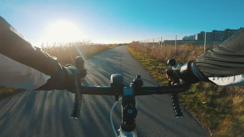 Point of view of man riding racing bicycle while sun sets in the horizon Stock Footage 98754671