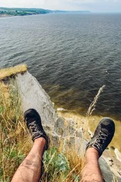 Point of view of man sitting on the edge of cliff Stock Photos