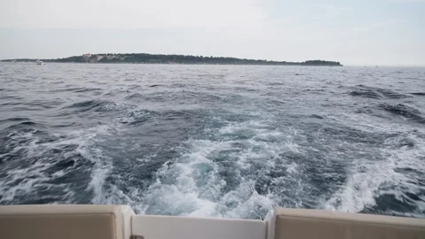 Point of view from a motorboat sailing away from an island, showing the churning Stockbeeldmateriaal 337409862