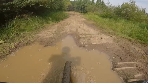 Point of view from mountain bike riding through mud puddles. Rider’s shadow in f Stock Footage 301110225