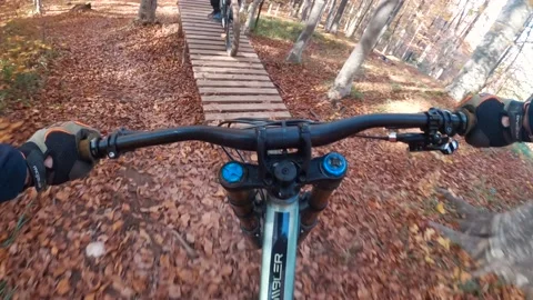 Point of view of mountain biker on mountain bike catching big air on wooden jump Stock Footage 150883865