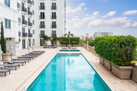 Point of view of the pool  in a hotel with several lounge chairs and umbrellas Stock Photos