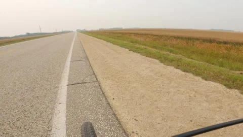 Point of view POV from a bicycle riding along a paved road surrounded in flat Stock Footage 306093893