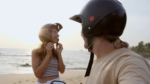 Point of view pov of couple on beach adjusting helmet before riding on scooter. 127861625
