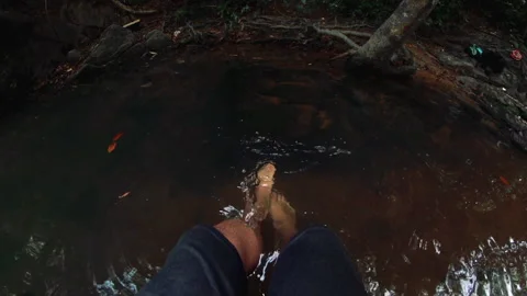 Point of view POV legs splashing in small pond. Barefoot person sitting on side Stock Footage 139643261