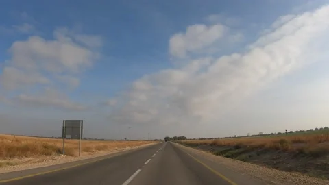 A point of view shot driving on a long straight road in desert grasslands at Stock Footage 200930101