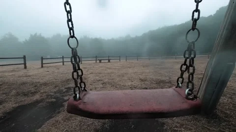 Point of view shot from an empty red swing moving back and forth in a deserted Video stock 344397700