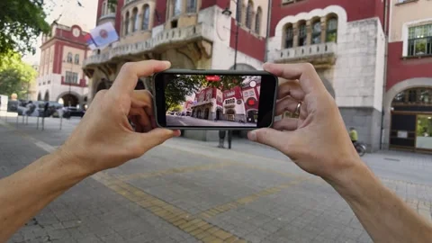 Point-of-View Shot of Hands Holding Smartphone Recording Historic Subotica City  Видео 342824688