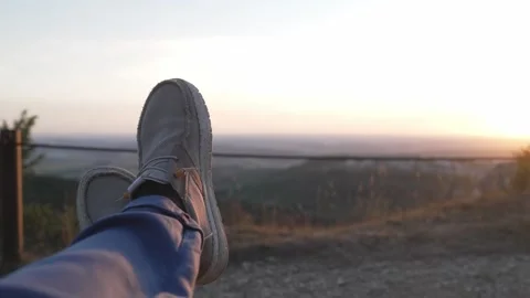 Point of view shot of legs in casual shoes at sunset viewpoint Stock Footage 341805933