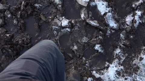 Point of view shot of legs as they walk over snow and mud Stock Footage 146245144