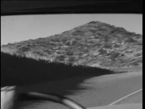 Point of view shot of man driving on desert road, 1960s Video stock 58856604