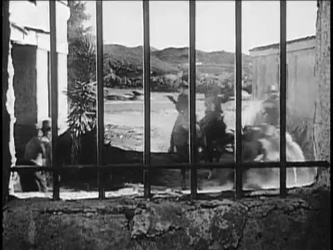 Point of view through prison bars of cowboys on horseback during shootout, 1940 스톡 동영상 61766776