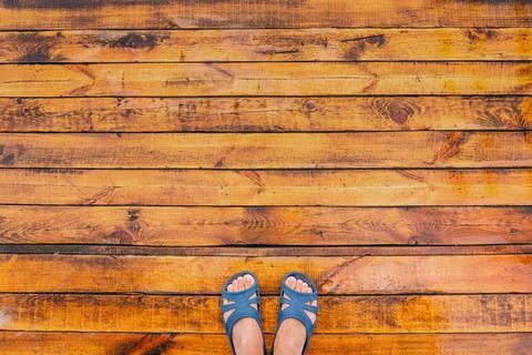 Point of view of two female legs standing on wet rainy wooden floor Stock Photos