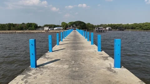Point of view walking along a concrete pier with blue posts Stock Footage 328489870