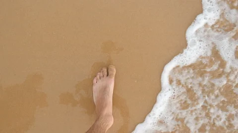 Point of view of young man stepping at the golden sand at sea beach. Male legs Vídeo Stock 125246028