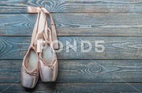 Pointe shoes ballet dance shoes with a bow of ribbons hang on a nail on a woo Stock Photos