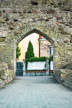 Pointed arch gate in an old stone defensive wall overlooking modern buildings Foto stock