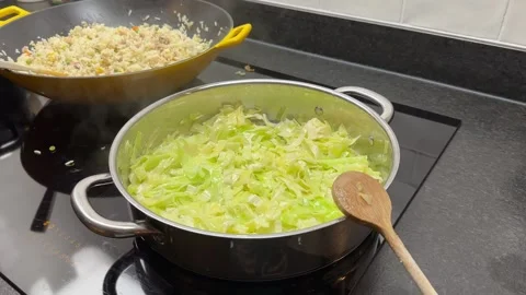 Pointed Cabbage being cooked next to a pan of Nasi Stock Footage 258439224