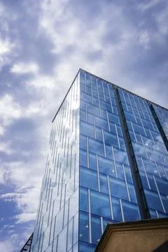 Pointed modern skyscraper with glass facade under dramatic sky, clean lines, Stock Photos
