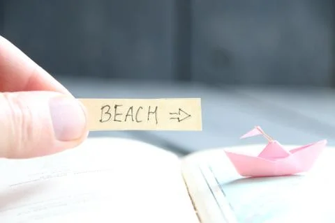 Pointer to beach and paper boat, summer vacation idea Stock Photos
