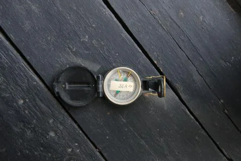 Pointer to the beach. Old compass and inscription. Stock Photos