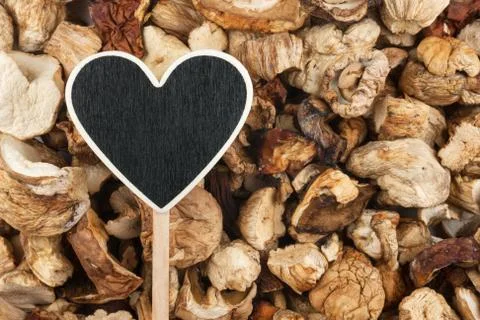 Pointer in the form of heart lies on dried mushrooms Stock Photos