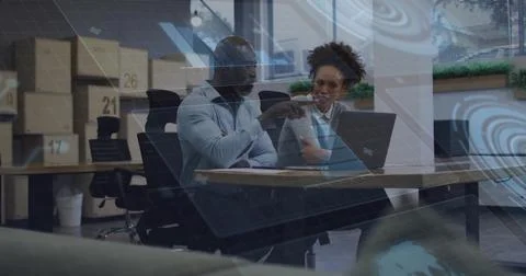 Pointing colleague discussing data visualization with coworker at office desk Stock Photos