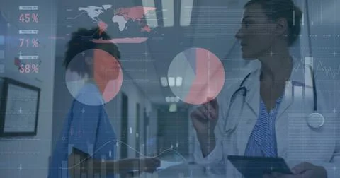 Pointing Dr in lab coat and nurse in scrubs consulting tablet in hospital Stock Photos
