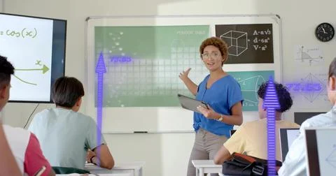 Pointing instructor in blue blouse holding tablet, teaching at classroom Stock Photos