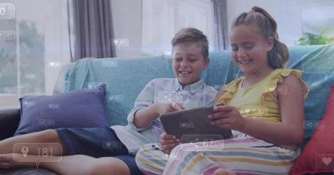 Pointing light-shirted boy and yellow-top girl sharing tablet at home, teal Stock Photos