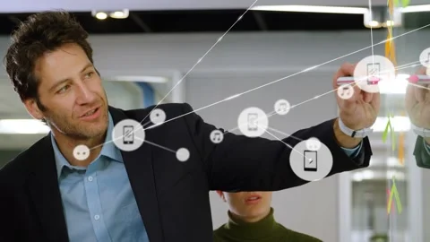 Pointing man in dark blazer drawing network links on glass wall during meeting, Stock Footage 332822354