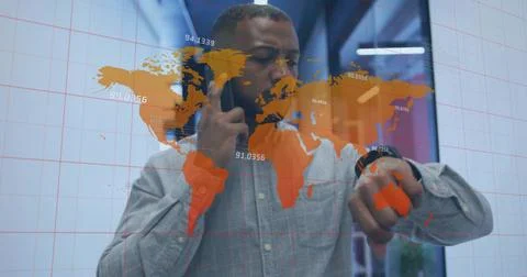 Pointing man tapping glass map at office, holding smartphone, wearing grey shirt 스톡 사진