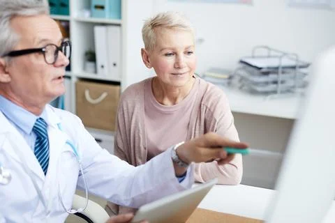 Pointing at monitor while explaining CAT scan to patient Stock Photos